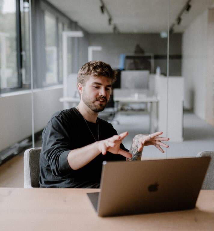 Ein junger Mann sitzt vor einem Laptop in der Agentur reaze