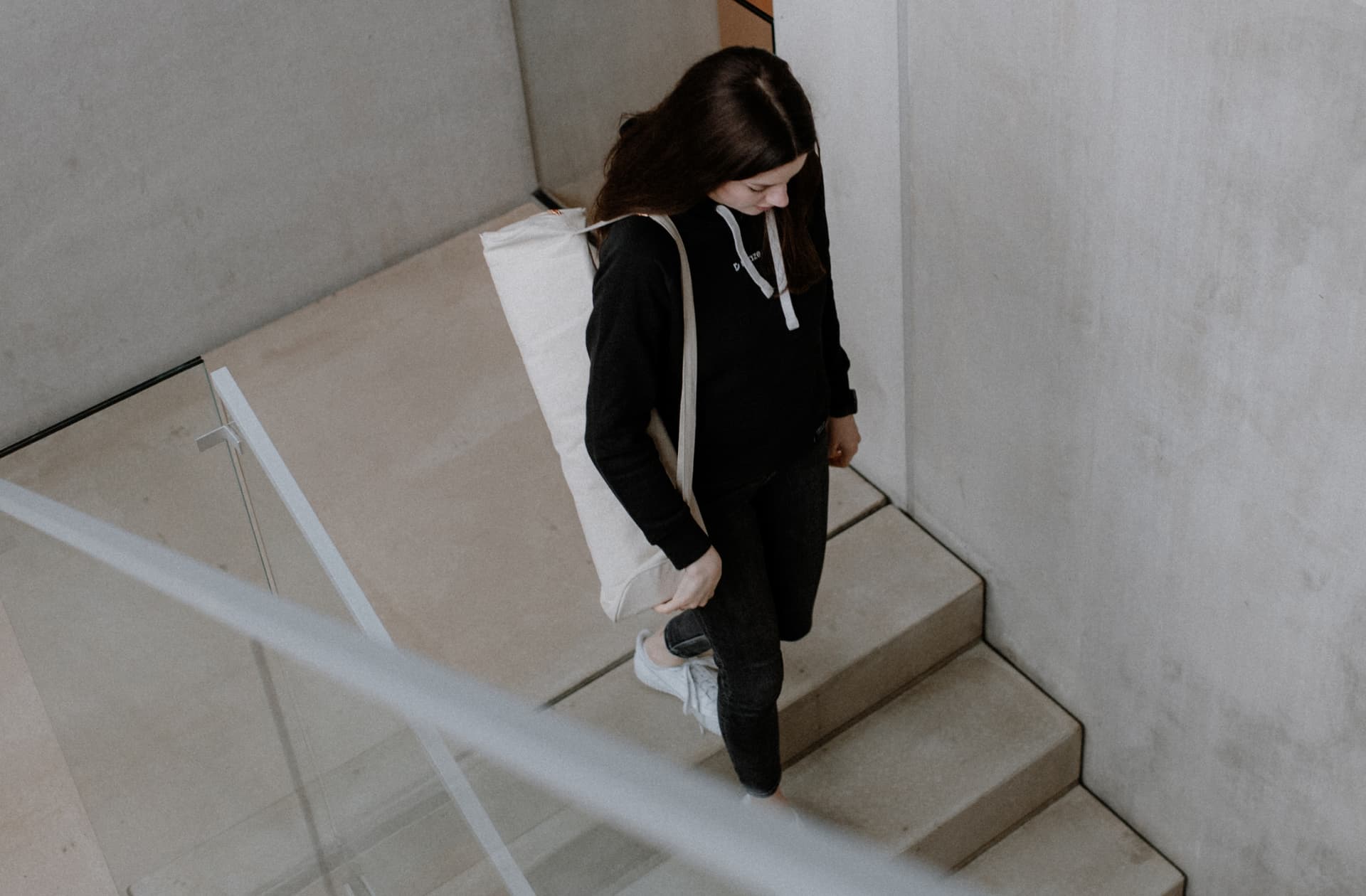 Eine junge Frau geht mit einer Yoga-Tasche eine Treppe runter