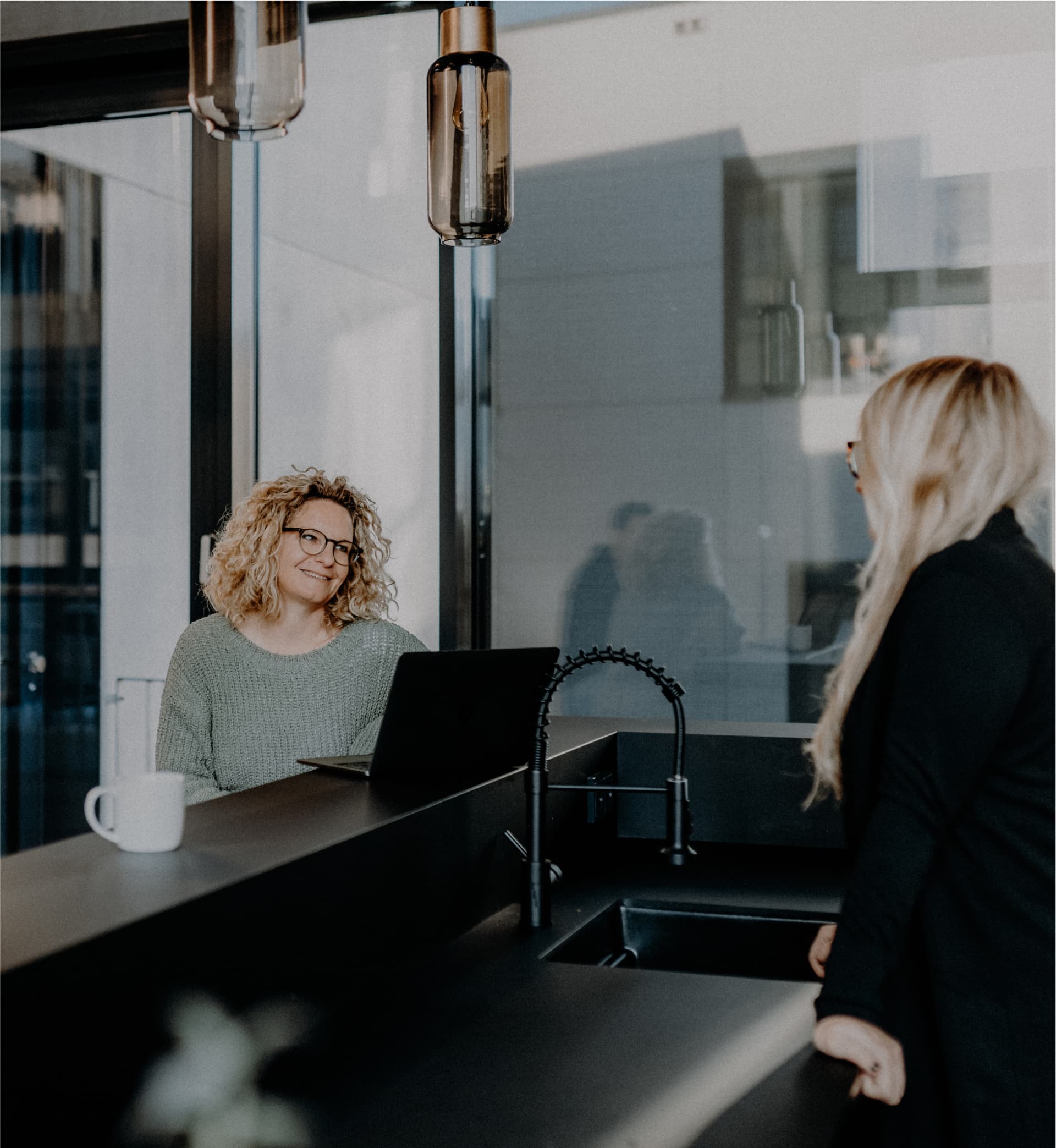 Zwei Frauen stehen an einer Theke in einem Büro und unterhalten sich.